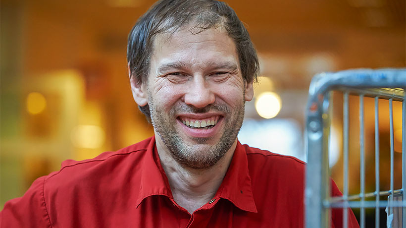 A man wearing a red shirt smiles at the camera.